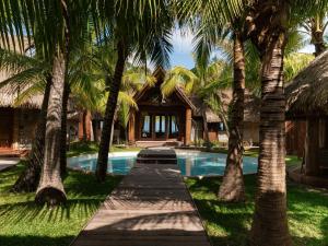 a pool with palm trees in front of a house at Le Tikehau by Pearl Resorts in Tikehau