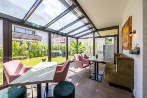 a conservatory with a dining room with pink chairs and a table at Hotel Am Martinsberg in Andernach