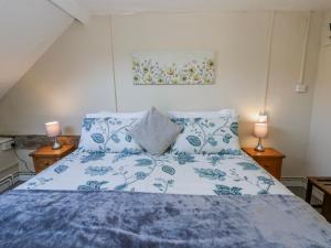 a bedroom with a blue and white bed with two lamps at Penlone Cottage in Rhayader