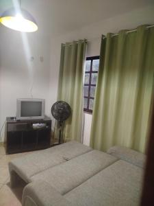 a bedroom with two beds and a television and a window at Condomínio Pousada Amarela 100 metros da Praia in Iguaba Grande