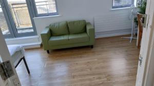 a green couch in a living room with wood floors at Newbury 2 in London