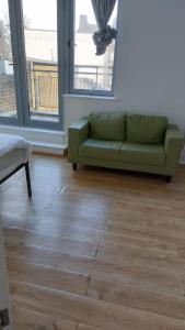a green couch sitting on a wooden floor in a room at Newbury 2 in London