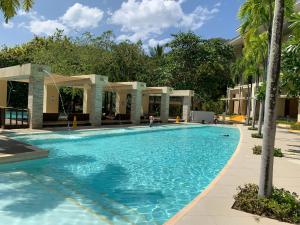 a swimming pool with blue water and palm trees at Shirley Pico de Loro 1BR in Nasugbu