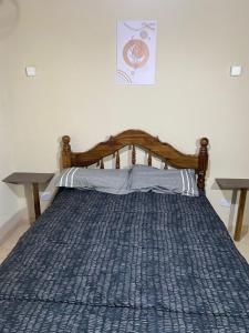 a bed with a blue comforter and two tables at Departamentos la lucia in Villa Paula de Sarmiento