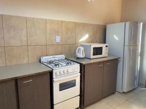 a kitchen with a stove and a microwave and a refrigerator at Departamentos la lucia in Villa Paula de Sarmiento
