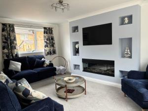a living room with blue couches and a fireplace at Palm Tree House in Filey