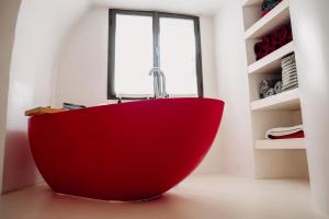 a red bath tub in a room with a window at Brána historic Boutique Apartments in Horažďovice