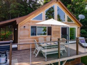 a cabin with a table and an umbrella on a deck at Red Cedar Haven Lakeside Tranquility in Sidney