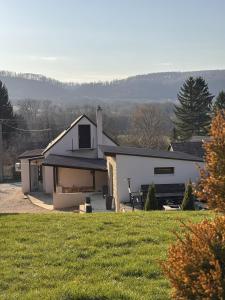 a white house with a grassy field in front of it at Milano Vendégház in Bakonybél