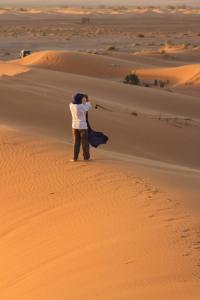 a man standing in the desert holding a scarf at Chez zakaria guest in Erfoud