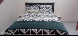 a bed with a black and white comforter and pillows at Recanto do Araguaia in Aragarças