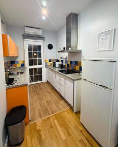 a kitchen with a white refrigerator and a wooden floor at Apto Tramontana 98 in El Puerto de Santa María