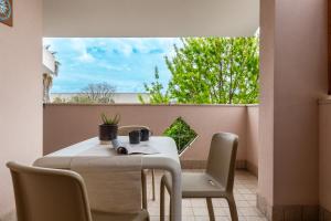 a table and chairs on a balcony with a window at Flamingo Poetto in Quartu SantʼElena