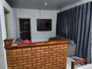 a living room with a brick fireplace with a television at Estalagem Alejandro in Cunha