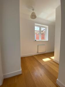 an empty room with a window and a wooden floor at Lovely Central Romsey Apartment in Romsey