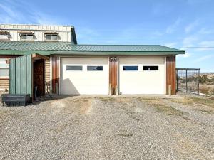 a house with two garage doors and a gravel driveway at Cedar Mountain Bunkhouse cabin in Montrose
