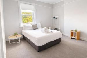 a white bedroom with a large bed with a window at Federal Hotel Mudgee in Mudgee