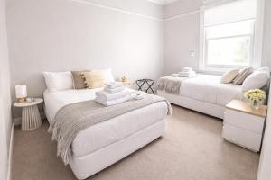 a white bedroom with two beds and a couch at Federal Hotel Mudgee in Mudgee