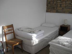 ペンザンスにあるTrezise Cottageのベッド2台、椅子、椅子が備わる客室です。