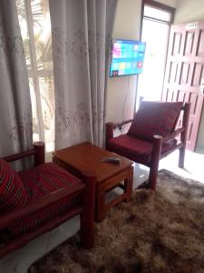 a living room with a chair and a table and a tv at Wasini gardens,, vingazini in Mtwapa