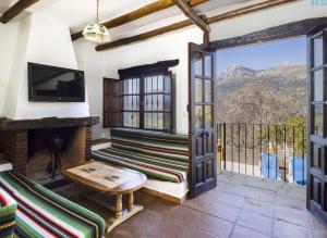 an open living room with a fireplace and a tv at Casa Rural Albahaca in Jimera de Líbar