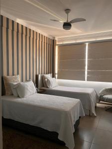a hotel room with two beds and a window at Apto Moderno no Centro - Completo e Confortável in Americana