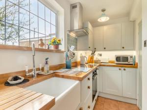 a kitchen with white cabinets and a large window at Little Crawfish Cottage in Thursford
