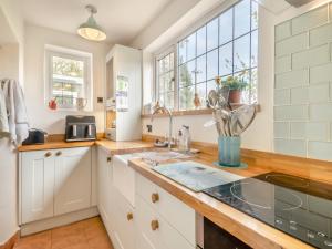 a kitchen with white cabinets and a sink at Little Crawfish Cottage in Thursford +15 photos