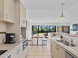 a kitchen with white cabinets and a living room at Elsinor 4 in Mulwala