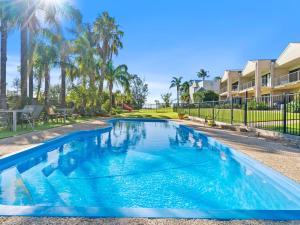 a blue swimming pool with palm trees and condos at Elsinor 4 in Mulwala