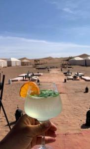 a person holding up a glass with an orange slice at Erg Chegaga Camp Excursions Stéphanie in Mhamid