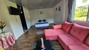 a living room with a pink couch and a bed at Finca los Bohíos in Santa Rosa de Cabal +27 photos