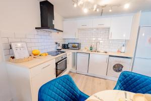 a kitchen with white cabinets and blue chairs at Modern 2 BR 2 Bath Flat With Balcony & Fast WiFi in Cardiff +22 photos