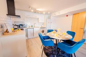 a kitchen and dining room with a table and blue chairs at Modern 2 BR 2 Bath Flat With Balcony & Fast WiFi in Cardiff