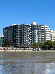 a large apartment building next to a beach with water at Portal Patagónico in Puerto Madryn