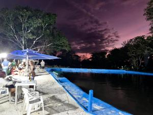 a group of people sitting under an umbrella by a pool at Lagos de Samarcanda in Cumaral +3 photos