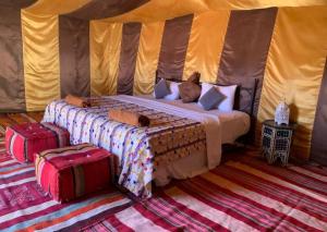 a bed in a tent with two cats laying on it at Erg Chegaga Camp Excursions Stéphanie in Mhamid