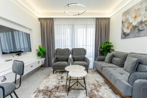 a living room with a couch and chairs and a tv at The Residence -Juction Mall in Nairobi
