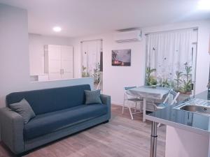 a living room with a blue couch and a kitchen at Apartamentos El Balconico in Arguedas