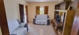a living room with a couch and a chair and a television at Sítio de Vavá in Gravatá