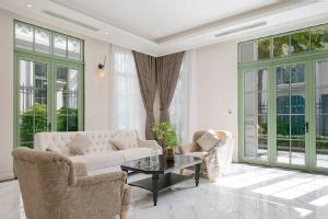 a living room with a couch and chairs and windows at Opus Villas Tropical Phu Quoc in Phú Quốc