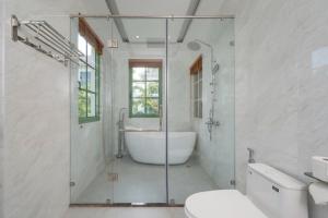 a bathroom with a tub and a glass shower at Opus Villas Tropical Phu Quoc in Phú Quốc