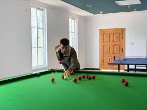 a man is playing pool on a pool table at Grand Montis Hotel in Abbottabad