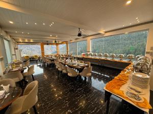 a restaurant with tables and chairs and large windows at Grand Montis Hotel in Abbottabad