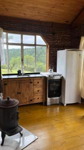 a kitchen with a stove and a refrigerator at Studio Rústico - Refúgio Arara Azul in Urubici