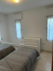a bedroom with two beds and a dresser and windows at Sans Souci in Gualeguaychú +5 photos