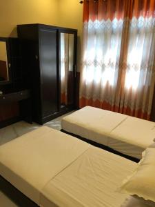 a bedroom with two beds and a window with curtains at Thresher shark inn in Fuvahmulah
