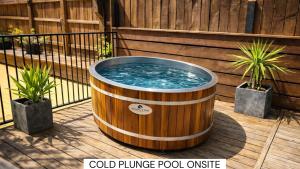 a large wooden tub on a deck with two plants at The Black Sheep Backpackers in Queenstown