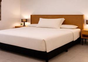 a bedroom with a large white bed with two lamps at Modern apartment with pool , Riviera Nayarit in Naranjo +7 photos