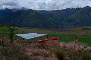 a building with a roof with mountains in the background at Camping tres nevados in Urubamba